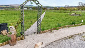A rural landscape with a wooden archway, a gravel path, and a fenced field. - 2 bedroom accommodation in Altham (Altham)