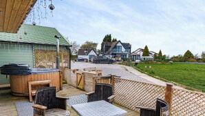 An outdoor patio area with wooden furniture, including tables and chairs, and a hot tub. - 2 bedroom accommodation in Altham (Altham)