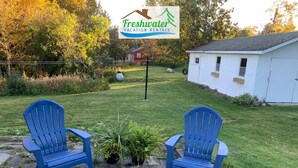 A sign for Freshwater Vacation Rentals with two blue Adirondack chairs in the foreground.