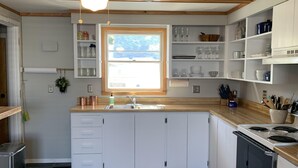 A modern kitchen with white cabinets, a central island, a built-in oven, and a window providing natural light.