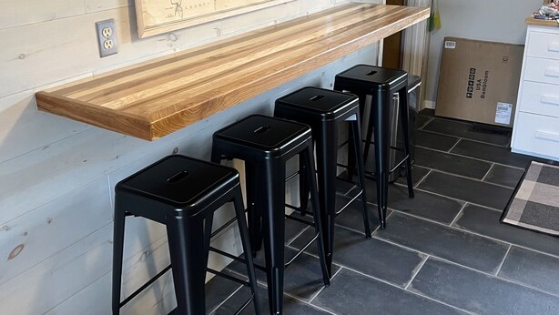 A kitchen with a wooden countertop, black stools, and a map on the wall.