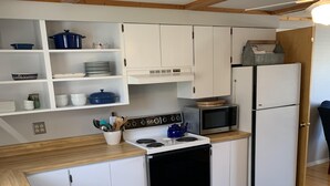 A compact kitchen with white cabinets, a stove, a microwave, and a refrigerator.