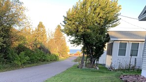A residential property with a paved driveway, a grassy lawn, and a house with a visible chimney.
