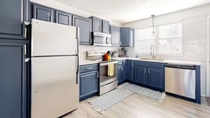A modern kitchen with dark blue cabinets, stainless steel appliances, and a herringbone-patterned backsplash. - Sunset Beach Bliss| Walk to Beach & Waterpark (Ocean City)