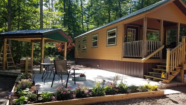 Una cabaña con porche techado, mobiliario exterior y terraza de madera.