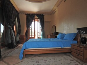 A bedroom with a wooden bed, a nightstand, a dresser, a mirror, and a window with curtains. - Jewel of Palmeraie (Marrakech)