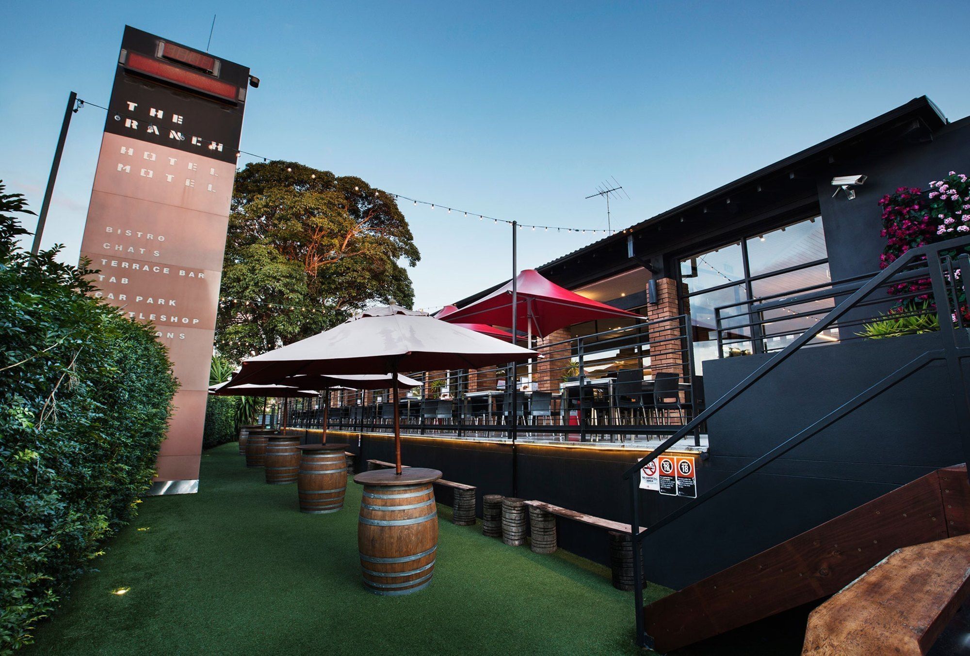 An outdoor bar area with wooden barrels, a staircase, and a sign for The Ranch Hotel.