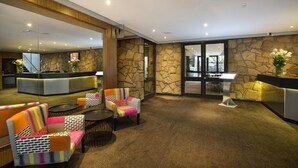 A lobby with a reception desk, seating area, and stone walls. - Nightcap at the Ranch Hotel (Sydney)