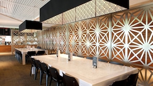 A modern restaurant with long tables and black chairs, a patterned wall, and a wooden ceiling. - Nightcap at the Ranch Hotel (Sydney)