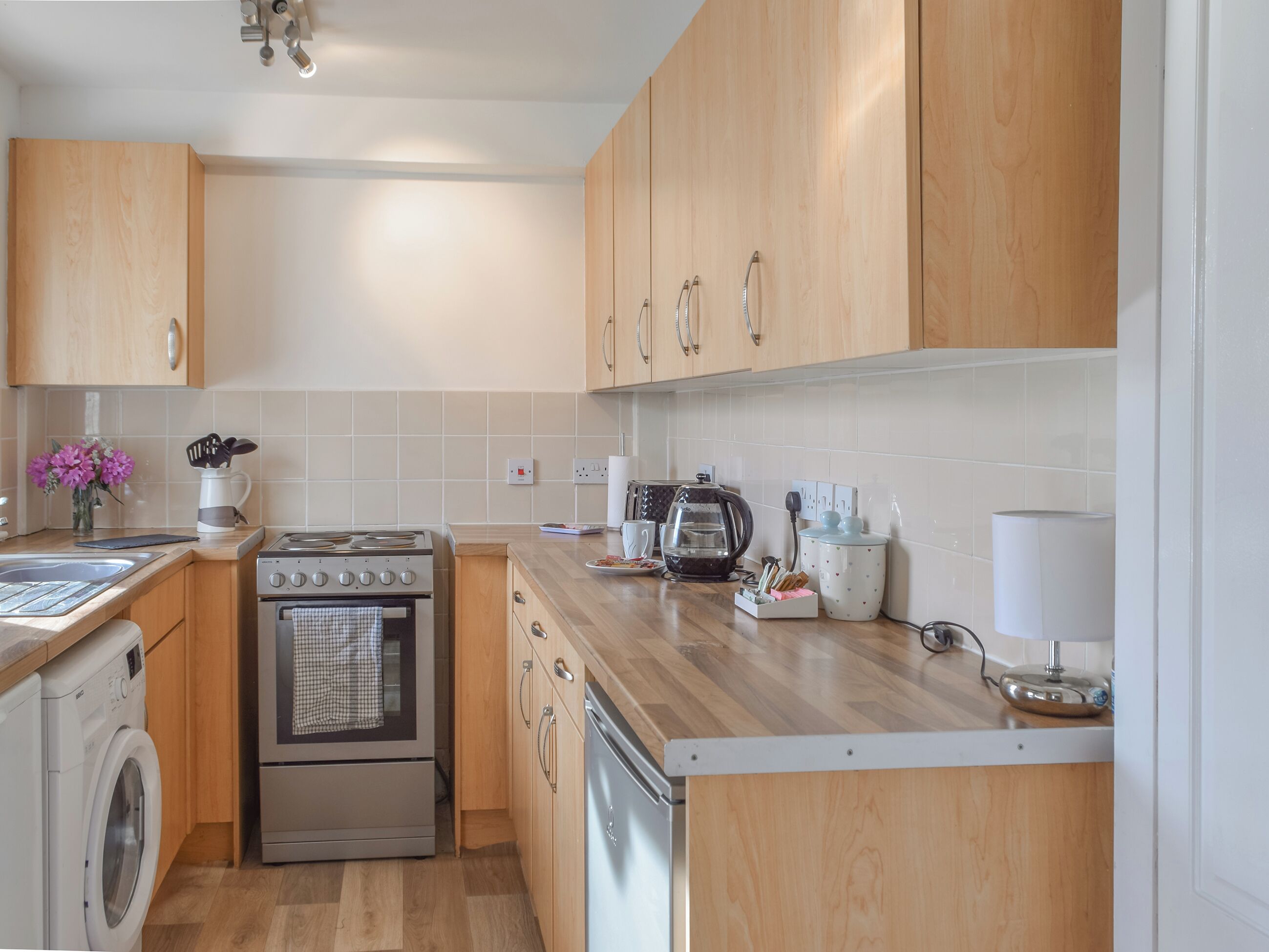 A modern kitchen with wooden cabinets, stainless steel appliances, and a tiled backsplash.