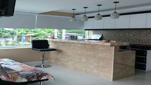 A modern kitchen with a central island, bar stools, and pendant lighting. - Pandora House Pattaya (Pattaya)