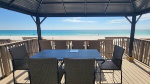 A covered outdoor seating area with a view of the beach.