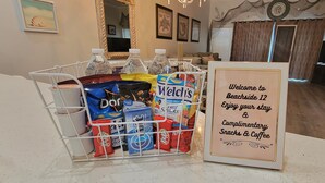 A snack and coffee station with various packaged snacks and bottled water.