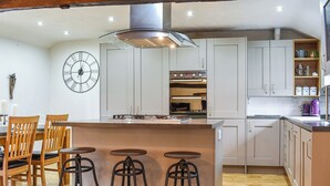Une cuisine moderne avec des tabourets de bar en bois, une horloge et un coin café.