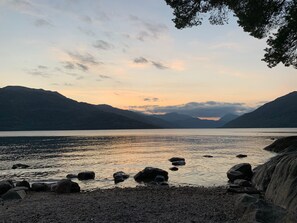 Un paisaje natural con un lago, montañas y una orilla rocosa.