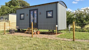 A small, single-story mobile home with a dark exterior, a front door, and two windows.