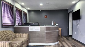 Una recepción con un computador, un cartel que prohíbe mascotas y un sofá.