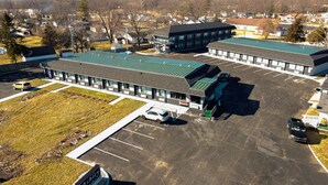 Un motel con estacionamiento, varias construcciones y un área verde.
