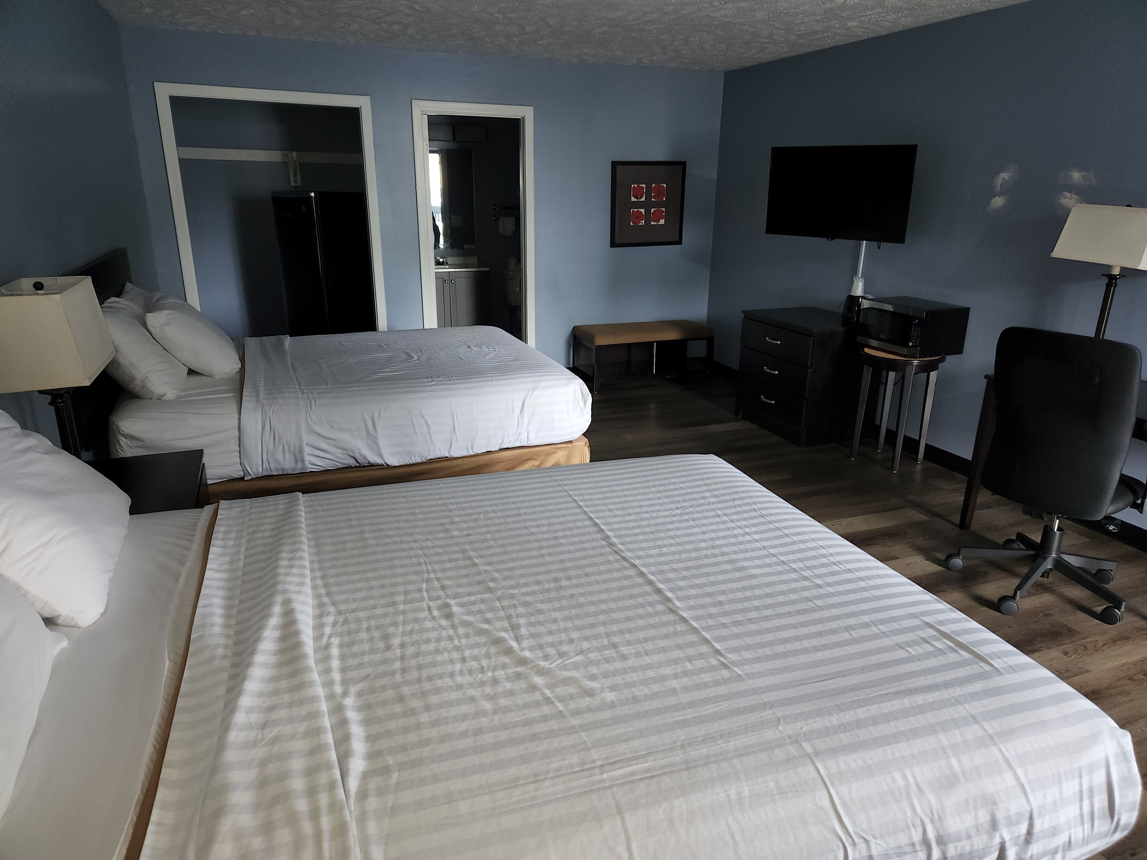 A hotel room with two beds, a desk with a computer, a TV, and a lamp.