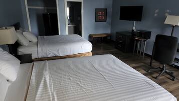 A hotel room with two beds, a desk with a computer, a TV, and a lamp.