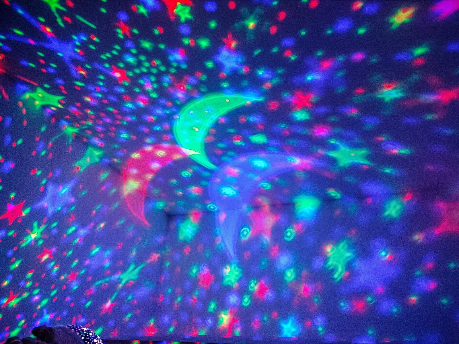 A room with a starry night projection on the ceiling, a crescent moon, and various constellations.
