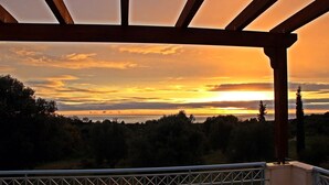 Vista do pôr do sol a partir de uma varanda com pérgola.