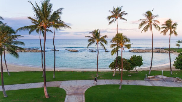 A coastal view with palm trees, a beach, and a clear sky. - You're Resort Home! Walk to Disney, Beach & Pool! (Kapolei)