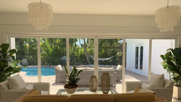 A spacious living area with a large window overlooking a pool and outdoor seating. - Modern Abode 3 miles from beach  (Lake Worth Beach)