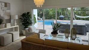 A modern living room with a view of a pool and outdoor furniture. - Modern Abode 3 miles from beach  (Lake Worth Beach)