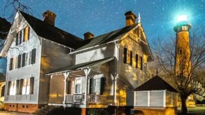 A two-story house with a porch and a lighthouse in the background. - Welcome to Saltwater Seaclusion! Heart of Corolla!  Walk to Everything! (Corolla)