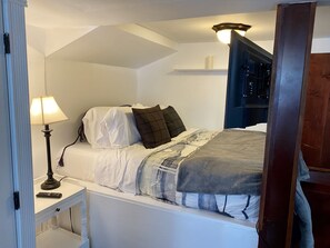 Un dormitorio con cama, lámpara de noche y mesita de noche.