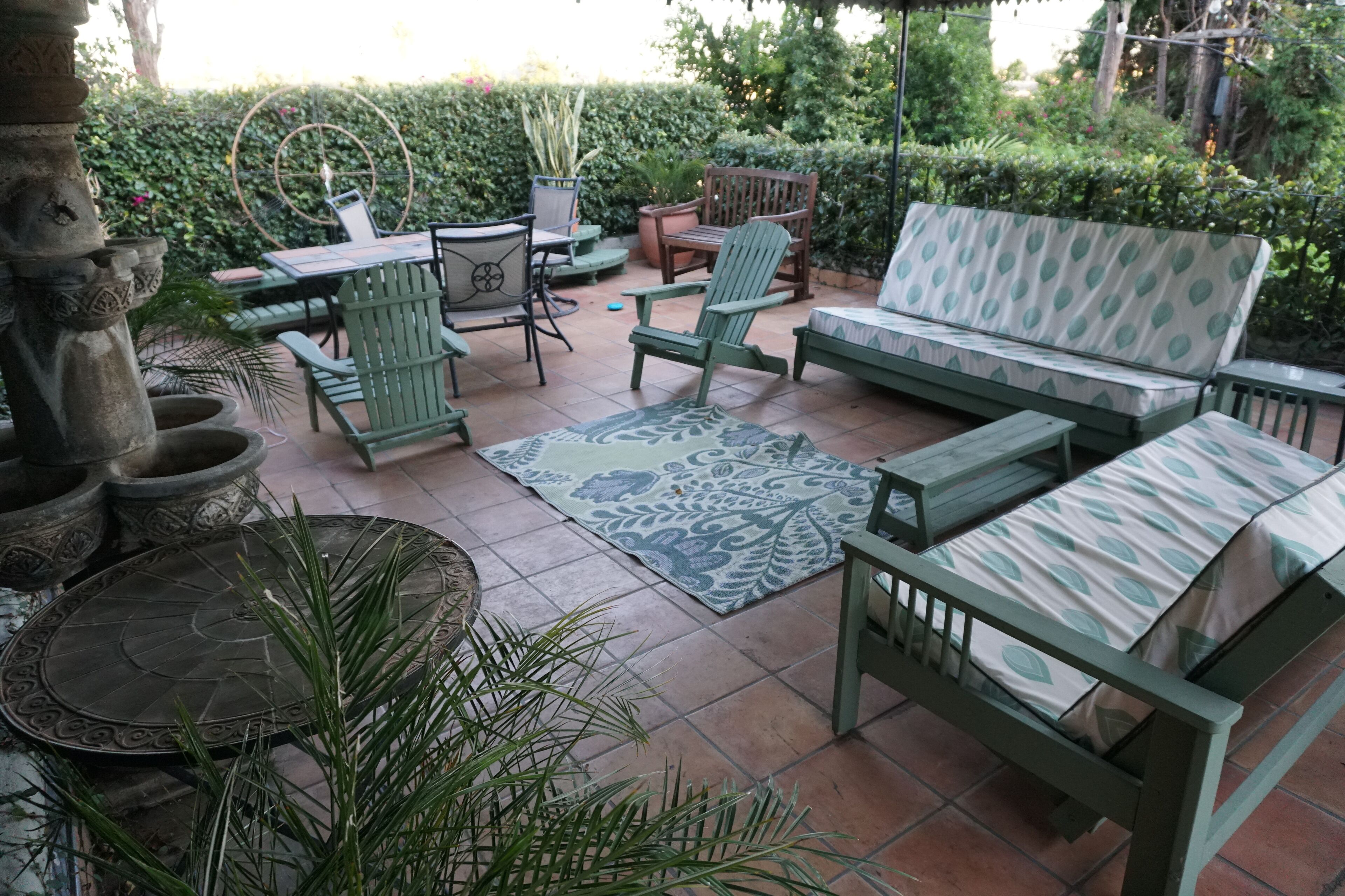 A patio area with a sofa, chairs, a table, and a decorative rug.