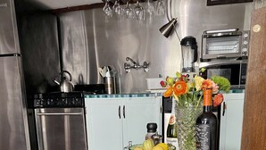 Una cocina con electrodomésticos de acero inoxidable, un frutero, un jarrón con flores y una nota sobre la encimera.