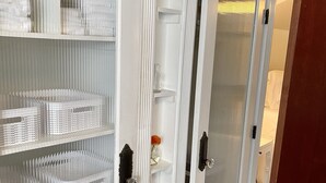 Un armario blanco de dos puertas con espejos y varios estantes.