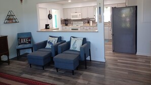 A living room with a sofa set, a kitchen in the background, and a refrigerator. - Cozy canal front home. Minutes from Sebring International Raceway. (Lake Placid)