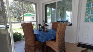 A dining area with wicker chairs and a table covered with a blue tablecloth. - Cozy canal front home. Minutes from Sebring International Raceway. (Lake Placid)