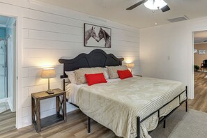 Ein Schlafzimmer mit Bett, Nachttischlampen, einem Holznachttisch, einem Deckenventilator und einem an der Wand hängenden Bild.