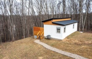 Cozy cabin nestled among the trees, offering a peaceful retreat with an entrance and a staircase leading up to the front door.