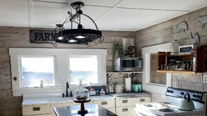 Una cocina con estética rústica, que incluye una estufa blanca, armarios de madera y un letrero de estilo campestre en la pared.