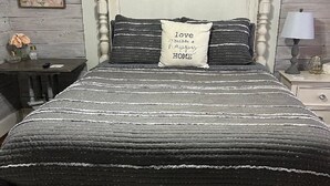 Una cama con cabecera blanca y dos almohadas, una con una frase motivacional.