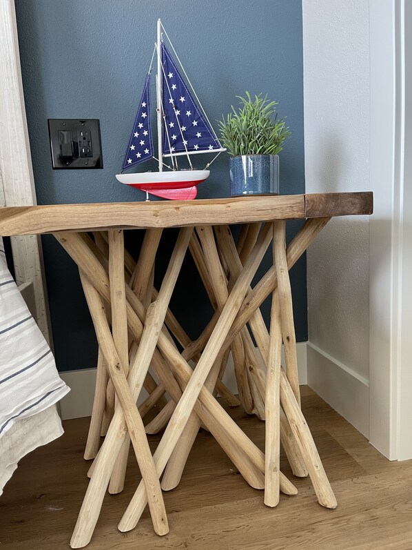 Een houten tafel met een model zeilboot en een bloempot erop.