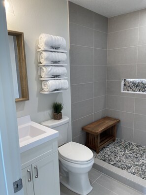 Un baño con inodoro, lavamanos y un pequeño taburete de madera.