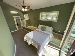 Ein Schlafzimmer mit Bett, Deckenventilator, Fenster und Tür.