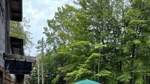 Una zona patio con un muro in pietra, un piccolo elemento d'acqua e un ombrello verde.