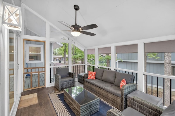 A covered porch with wicker furniture, a ceiling fan, and a glass door leading outside.