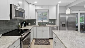 Una cocina moderna con armarios blancos, un refrigerador de acero inoxidable, un microondas y una estufa negra.
