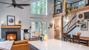 A modern interior with a fireplace, a dining area, and a staircase leading to an upper level.