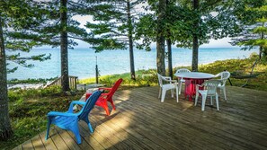 A wooden deck with outdoor furniture, overlooking a body of water. - Lake Michigan beachside cottage in Good Hart (Harbor Springs)