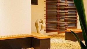 A modern interior with a minimalist design, featuring a sculptural element, a geometric wall panel, and a seating area with a pebble ground. - Essence Apartments Chermside (Brisbane)