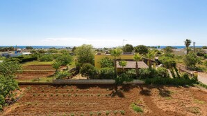 A residential area with a view of the sea, featuring houses with terracotta roofs, a garden, and a clear sky. - Villetta Della Fonte (Racale)